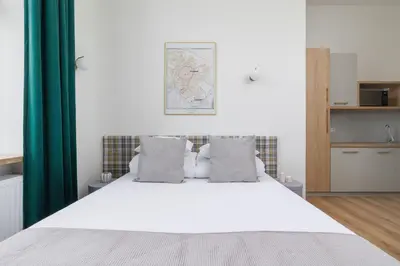 a bedroom with a white bed with green curtains at Studio for 2 - Augustiańska 1 - Kazimierz in Kraków