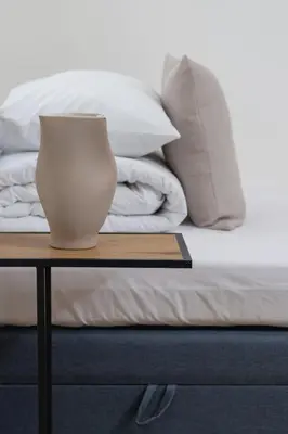 a white vase sitting on a table next to a bed at Cozy studio - Augustiańska 1 street in Kraków