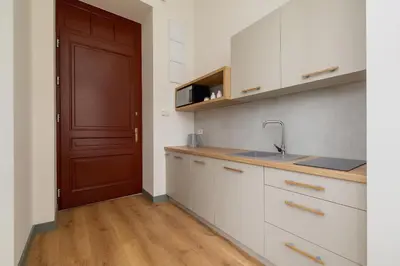a kitchen with white cabinets and a brown door at 2-bedroom apartment - Augustiańska 1 street in Kraków