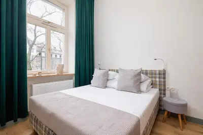 a bedroom with a bed with green curtains and a window at 2-bedroom apartment - Augustiańska 1 street in Kraków