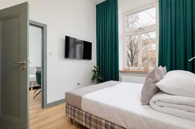a bedroom with a bed with green curtains and a flat screen tv at 2-bedroom apartment - Augustiańska 1 street in Kraków