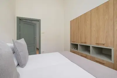 a bedroom with a white bed and a wooden cabinet at Cozy apartment - Augustiańska 1 street in Kraków
