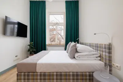 a bedroom with a bed with green curtains and a television at Apartment for 6 people - Augustiańska 1 in Kraków