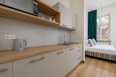 a kitchen with white cabinets and a bed in a room at Apartment for 6 people - Augustiańska 1 in Kraków