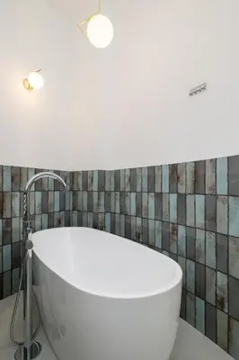 a white tub in a bathroom with a tile wall at Apartment for 6 - Augustiańska 1 street in Kraków