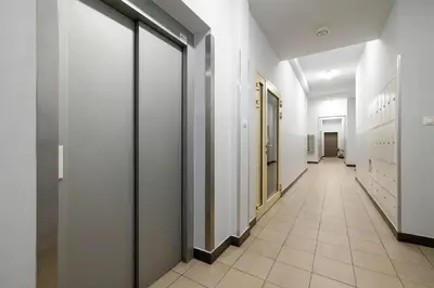 a corridor of a hallway with white walls and tile floors at Klimatyzowany Apartament z Balkonem i Przestrzenią do Pracy Lokalizacja Blisko Wisły by Noclegi Renters in Kraków