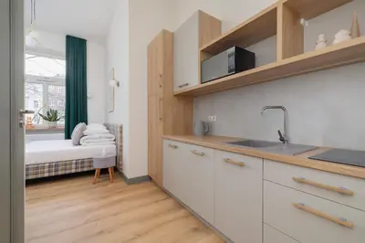 a kitchen with white cabinets and a bed in a room at Kazimierz- Augustiańska 1- Studio with AC in Kraków