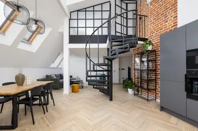 a kitchen and dining room with a spiral staircase in a loft at Apartment with mezzanine - Augustiańska 1 in Kraków