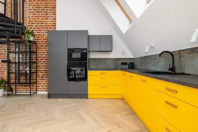 a kitchen with yellow cabinets and a black refrigerator at Apartment with mezzanine - Augustiańska 1 in Kraków