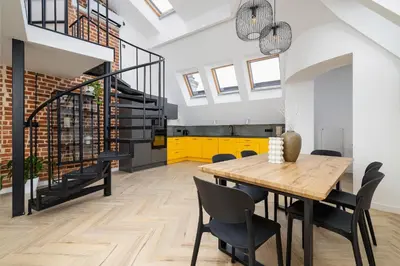 a dining room with a wooden table and chairs at Apartment with mezzanine - Augustiańska 1 in Kraków
