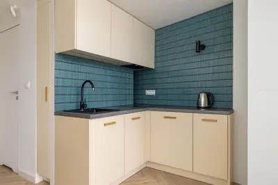a kitchen with white cabinets and blue tiles at Apartment with AC- Augustiańska 1 in Kraków