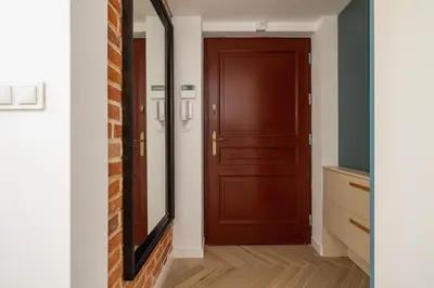 a hallway with a mirror and a brown door at Apartment with AC- Augustiańska 1 in Kraków