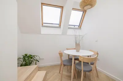 a dining room with a table and chairs and two windows at Apartment with AC- Augustiańska 1 in Kraków