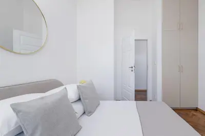 a white bedroom with a bed and a mirror at 2 Bedroom Apartment for 6 - Augustiańska 1 street in Kraków