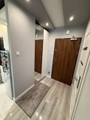 a hallway with a wooden door and a kitchen at Mieszkanie z parkingiem podziemnym Przewóz Podgórze in Kraków