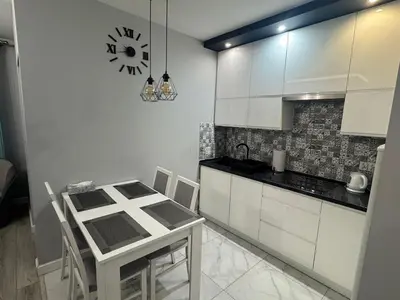 a kitchen with a table and a clock on the wall at Mieszkanie z parkingiem podziemnym Przewóz Podgórze in Kraków