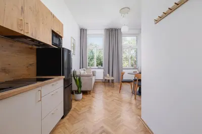 a kitchen with white cabinets and a living room at Jewish Quarter - Augustiańska 1 street in Kraków