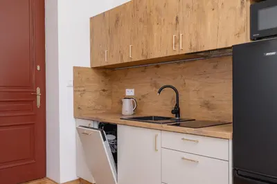 a kitchen with white cabinets and a sink and a black refrigerator at Jewish Quarter - Augustiańska 1 street in Kraków