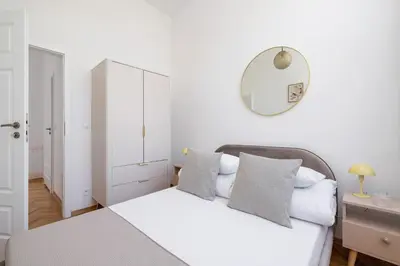 a white bedroom with a bed and a mirror at 1 bedroom Apartment - Augustiańska 1 street in Kraków