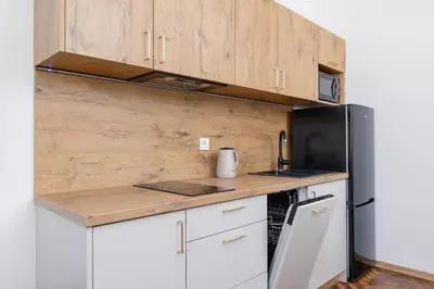 a kitchen with white cabinets and a black refrigerator at 1 bedroom Apartment - Augustiańska 1 street in Kraków