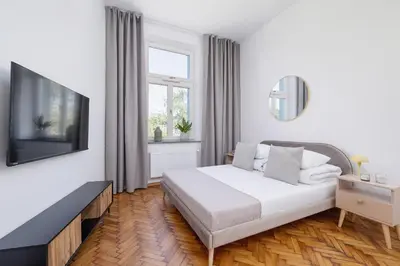 a white bedroom with a bed and a television at Studio with AC - Augustiańska 1 in Kraków
