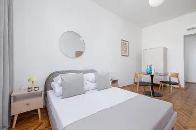 a white bedroom with a bed and a mirror at Studio with AC - Augustiańska 1 in Kraków