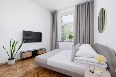 a white bedroom with a bed and a tv at Studio with AC - Augustiańska 1 in Kraków