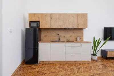 a kitchen with a black refrigerator and white cabinets at Studio with AC - Augustiańska 1 in Kraków