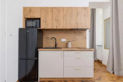 a kitchen with a black refrigerator and white cabinets at Apartment with the balcony - Augustiańska 1 in Kraków