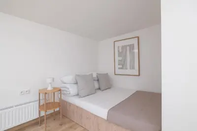 a white bedroom with a bed and a table at Cosy loft apartment - Jewish Quarter in Kraków
