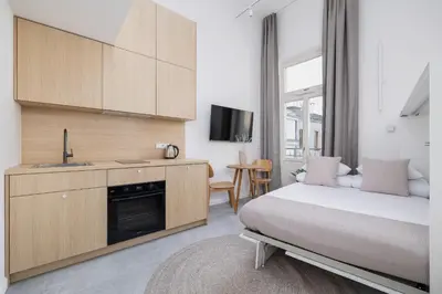 a bedroom with a bed and a sink and a kitchen at Cozy studio - Augustiańska 1 in Kraków