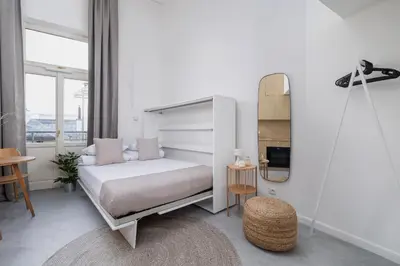 a white bedroom with a bed and a mirror at Cozy studio - Augustiańska 1 in Kraków