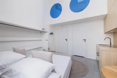 a white room with a bed and a kitchen at Cozy studio - Augustiańska 1 in Kraków