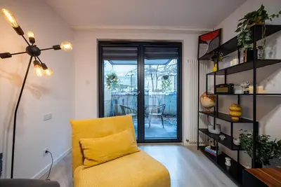 a living room with a yellow chair and a sliding glass door at Verona ElevenFive in Kraków