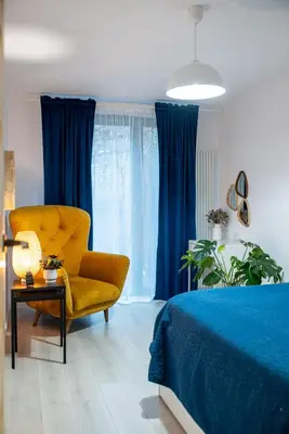 a bedroom with a yellow chair and blue curtains at Verona ElevenFive in Kraków