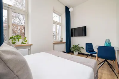a bedroom with a bed and a tv and two chairs at Apartment - Augustiańska 1 street in Kraków