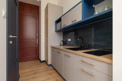a kitchen with white cabinets and a sink and a red door at Apartment - Augustiańska 1 street in Kraków