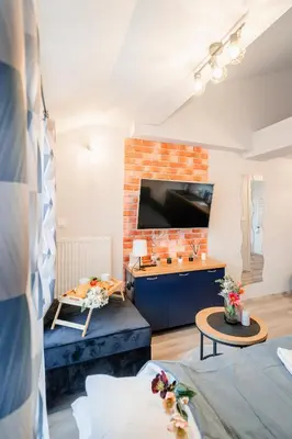 a living room with a large television and a brick wall at Kraków Studio - Vistula River nearby - by Rentujemy in Kraków