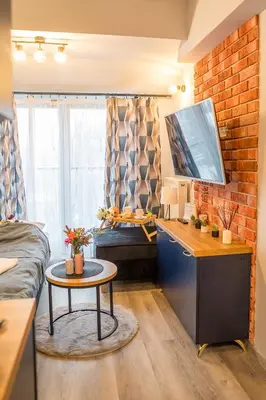 a room with a desk with a tv and a brick wall at Kraków Studio - Vistula River nearby - by Rentujemy in Kraków