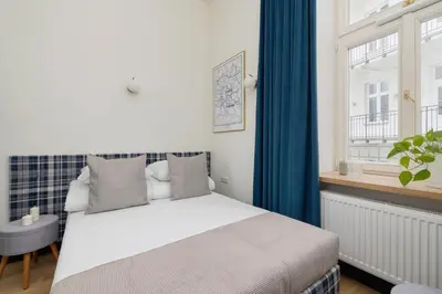 a bedroom with a bed with blue curtains and a window at Apartment- AC - Augustiańska 1- Jewish Quarter in Kraków