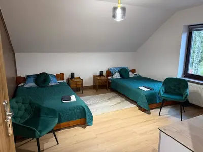 a room with two beds and a chair in it at Wynajmowanie pokoi in Szczyglice