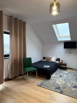 a bedroom with a bed and a green chair at Wynajmowanie pokoi in Szczyglice