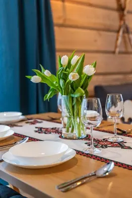 a table with a vase of white flowers and glasses at Burnosówka in Nowy Targ