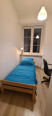 a bedroom with a bed with blue sheets and a window at Centrally located cozy apartment in Kraków