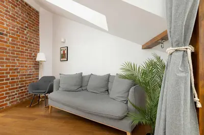 a couch in a living room with a brick wall at Modern Apartment with Air Conditioning and Terrace near Old Town in Cracow by Noclegi Renters in Kraków