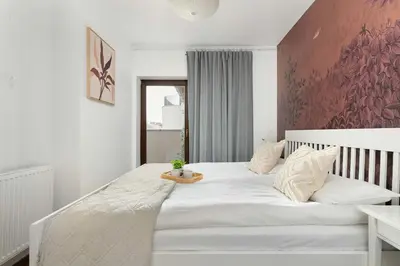 a bedroom with a large white bed with a red wall at Modern Apartment with Air Conditioning and Terrace near Old Town in Cracow by Noclegi Renters in Kraków