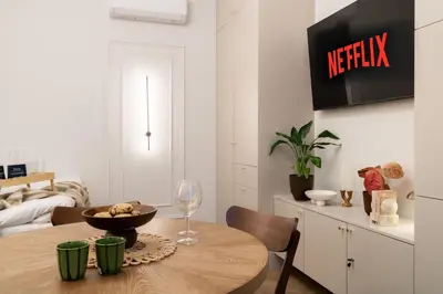 a dining room with a table and a tv on the wall at Malila Premium Apartments Estery Boutique in Kraków