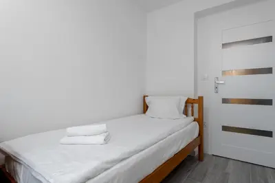 a bed with white sheets and pillows in a room at Bronowice Spacious Apartment by BookingHost in Kraków