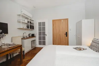 a bedroom with a bed and a desk and a kitchen at Antique Apartments - Tomasza 6A in Kraków