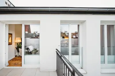 a white house with glass doors and a balcony at Antique Apartments - Tomasza 6A in Kraków